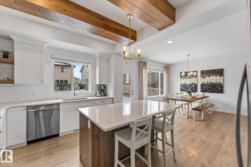 The property features a kitchen with white cabinetry, a kitchen island, and stainless steel appliances - 13 Spring Link, Spruce Grove, AB - Indoor