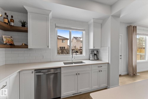 This kitchen features white cabinetry, a stainless steel sink, and a stainless steel dishwasher - 13 Spring Link, Spruce Grove, AB - Indoor Photo Showing Kitchen With Double Sink