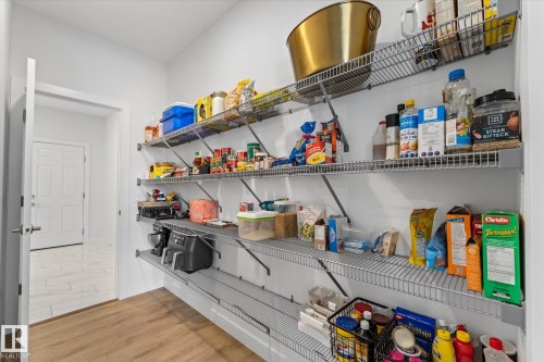 This pantry features extensive wire shelving providing ample storage, a light wood-look floor, and white walls - 13 Spring Link, Spruce Grove, AB - Indoor With Storage
