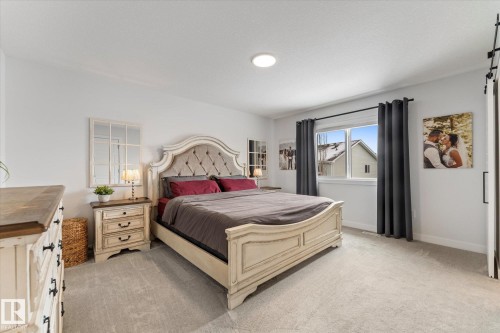 This room features light-colored carpeting, a window with dark curtains, and a white ceiling with a flush-mount light fixture - 13 Spring Link, Spruce Grove, AB - Indoor Photo Showing Bedroom