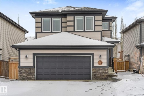 This property features a two-story exterior with a two-car garage, light-colored siding, and a stone facade - 13 Spring Link, Spruce Grove, AB - Outdoor