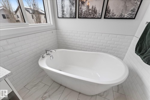 Bathroom featuring a freestanding bathtub, tiled walls, and tiled flooring - 13 Spring Link, Spruce Grove, AB - Indoor Photo Showing Bathroom