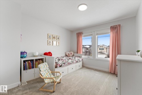 This bright room features neutral carpeting, white walls, and a window with pink curtains - 13 Spring Link, Spruce Grove, AB - Indoor Photo Showing Bedroom