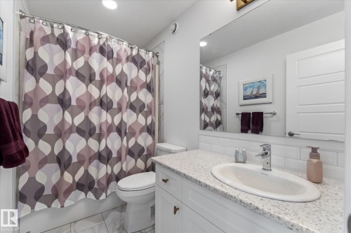 This bathroom features a shower and tub combination, a toilet, and a vanity with an integrated sink and chrome faucet - 13 Spring Link, Spruce Grove, AB - Indoor Photo Showing Bathroom