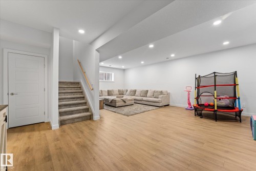 Spacious lower level featuring light-colored flooring, recessed lighting, and a carpeted staircase with a wooden handrail - 13 Spring Link, Spruce Grove, AB - Indoor Photo Showing Other Room