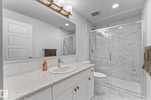 The bathroom features a modern vanity with a white countertop and a rectangular sink - 13 Spring Link, Spruce Grove, AB - Indoor Photo Showing Bathroom