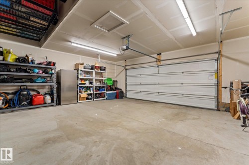 Spacious garage featuring a concrete floor, overhead lighting, and a white garage door - 13 Spring Link, Spruce Grove, AB - Indoor Photo Showing Garage