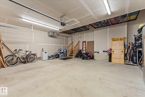 Spacious garage featuring a concrete floor, exposed drywall, and overhead lighting - 13 Spring Link, Spruce Grove, AB - Indoor Photo Showing Garage