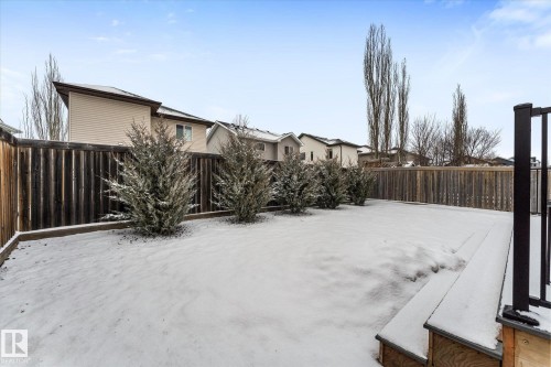 The property features a fenced yard with a wooden deck and established shrubbery along the fence line - 13 Spring Link, Spruce Grove, AB - Outdoor