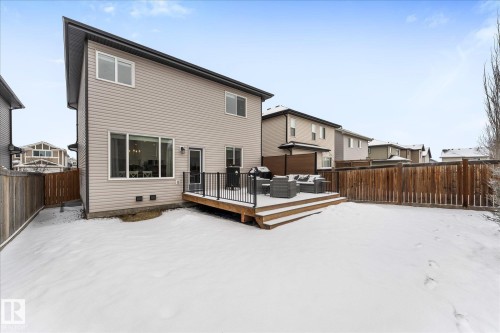 The property features a spacious backyard with a wooden deck, a wooden fence, and a large window providing views of the outdoor space - 13 Spring Link, Spruce Grove, AB - Outdoor With Deck Patio Veranda With Exterior