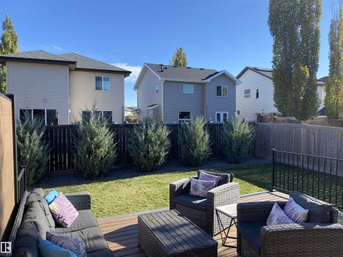 The property features a well-maintained yard with a lawn, a wooden deck, and mature shrubs - 13 Spring Link, Spruce Grove, AB - Outdoor With Deck Patio Veranda With Exterior