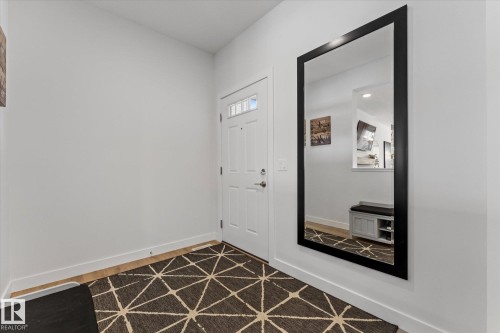 The entryway features a white paneled door with windowpanes and a large framed mirror - 13 Spring Link, Spruce Grove, AB - Indoor Photo Showing Other Room