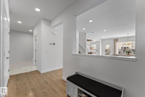 The entryway features durable flooring, recessed lighting, and a view into the open concept living areas with a window and a glass panel door - 13 Spring Link, Spruce Grove, AB - Indoor Photo Showing Other Room