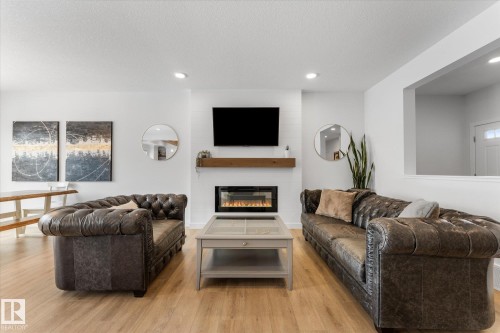 Living area featuring light wood flooring, an electric fireplace with a wooden mantel, and recessed lighting - 13 Spring Link, Spruce Grove, AB - Indoor Photo Showing Living Room With Fireplace