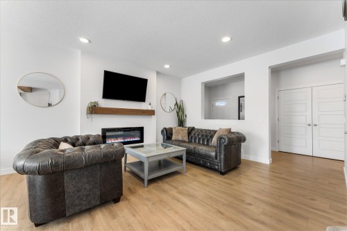 Living area featuring light wood flooring, an electric fireplace with a wood mantle, and recessed lighting - 13 Spring Link, Spruce Grove, AB - Indoor Photo Showing Living Room With Fireplace