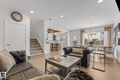 The property features light wood flooring, a staircase with carpeted steps, and recessed lighting - 13 Spring Link, Spruce Grove, AB - Indoor Photo Showing Living Room