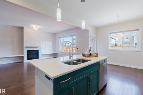 Open concept living space featuring a kitchen island with a double sink, a built-in dishwasher, and pendant lighting - 4875 Wright Drive, Edmonton, AB - Indoor Photo Showing Kitchen With Fireplace With Double Sink