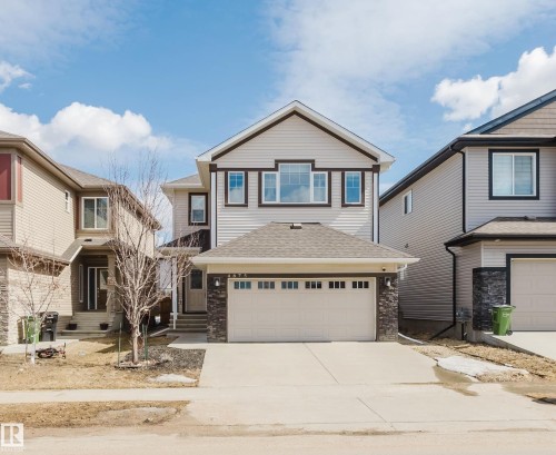 The property features a two-story exterior with light-colored siding, a dark roof, and a prominent front-facing garage - 4875 Wright Drive, Edmonton, AB - Outdoor With Facade