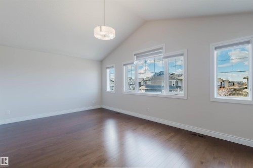 Spacious room featuring vaulted ceilings, a contemporary ceiling fixture, hardwood floors, and large windows providing natural light - 4875 Wright Drive, Edmonton, AB - Indoor Photo Showing Other Room