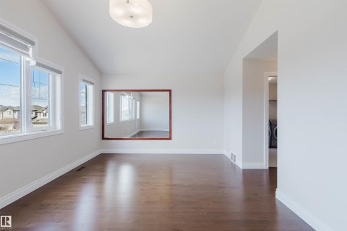 This room features hardwood flooring, white walls, and a vaulted ceiling with a modern light fixture - 4875 Wright Drive, Edmonton, AB - Indoor Photo Showing Other Room