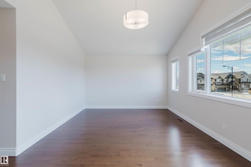 This room features a vaulted ceiling, dark hardwood floors, and windows with white trim - 4875 Wright Drive, Edmonton, AB - Indoor Photo Showing Other Room