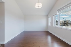 This room features a vaulted ceiling, dark hardwood floors, and windows with white trim - 