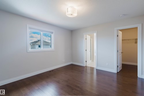 The room features lustrous hardwood flooring, a window offering views of the surrounding neighborhood, and a ceiling light fixture - 4875 Wright Drive, Edmonton, AB - Indoor Photo Showing Other Room