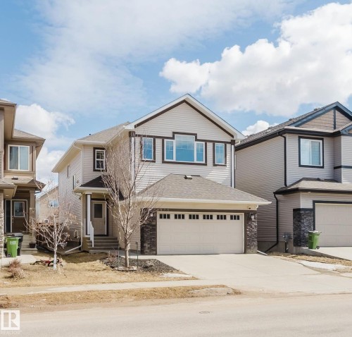 This property features a two-story design with a two-car garage, light-colored siding, and stone accents on the facade - 4875 Wright Drive, Edmonton, AB - Outdoor With Facade
