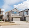 This property features a two-story design with a two-car garage, light-colored siding, and stone accents on the facade - 4875 Wright Drive, Edmonton, AB  - Outdoor With Facade 