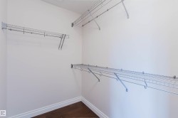 Walk-in closet featuring white walls, wire shelving, and hardwood flooring - 