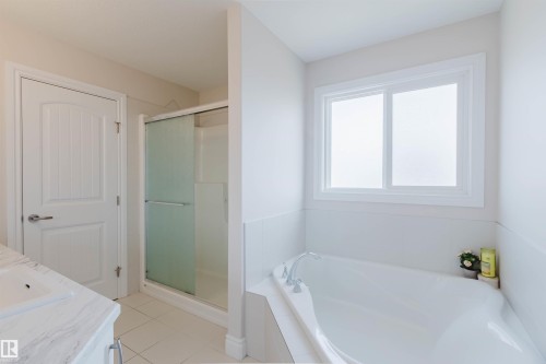 This bathroom features a spacious bathtub, a window with frosted glass, and a separate shower with a sliding glass door - 4875 Wright Drive, Edmonton, AB - Indoor Photo Showing Bathroom