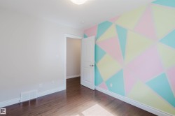 The room features dark hardwood floors and a wall with a geometric pattern in pastel colors - 