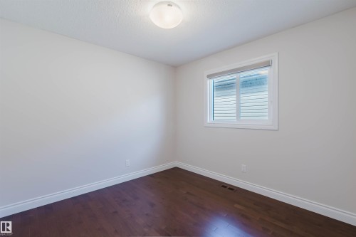 This room features hardwood floors, white baseboards, and a window with blinds providing natural light - 4875 Wright Drive, Edmonton, AB - Indoor Photo Showing Other Room