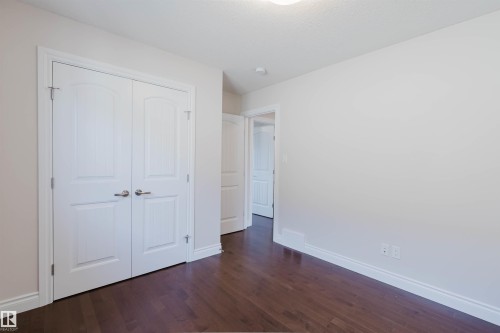 This room features dark hardwood flooring, white baseboards, and light-colored walls - 4875 Wright Drive, Edmonton, AB - Indoor Photo Showing Other Room