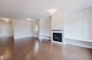 This inviting space features hardwood floors, a fireplace with a dark wood mantle, and a decorative paneled wall - 4875 Wright Drive, Edmonton, AB  - Indoor Photo Showing Living Room With Fireplace 