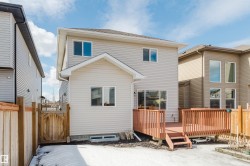 The property features a two-story exterior with light-colored siding and white trim - 