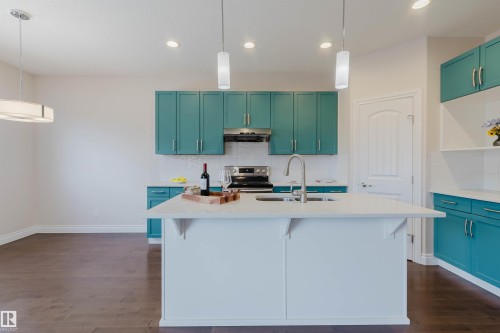 Contemporary kitchen featuring teal cabinetry, a kitchen island with a sink, recessed lighting, and dark hardwood flooring - 4875 Wright Drive, Edmonton, AB - Indoor Photo Showing Kitchen With Upgraded Kitchen