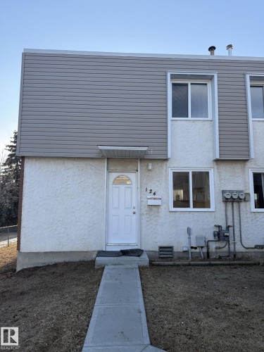 The property features a two-story exterior with a combination of textured stucco and horizontal siding, a white front door with an arched window, and a concrete pathway leading to the entrance - 124 Cornell Court, Edmonton, AB - Outdoor
