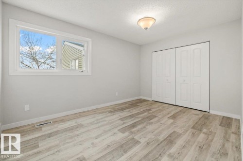 This room features light-toned flooring, a window providing natural light, and a bi-fold closet - 12C Castle Terrace, Edmonton, AB - Indoor Photo Showing Other Room