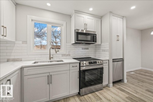 The kitchen features light-colored cabinetry, a stainless steel sink with a gooseneck faucet, a subway tile backsplash, and light countertops - 12C Castle Terrace, Edmonton, AB - Indoor Photo Showing Kitchen With Upgraded Kitchen