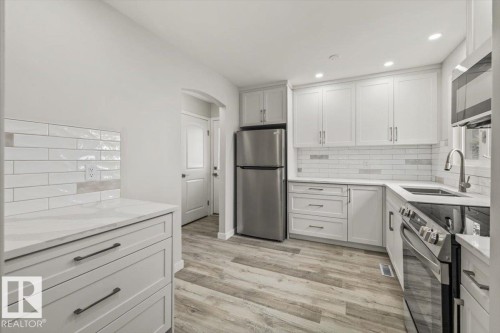 The kitchen features white cabinetry, white countertops, and a white subway tile backsplash - 12C Castle Terrace, Edmonton, AB - Indoor Photo Showing Kitchen With Double Sink With Upgraded Kitchen