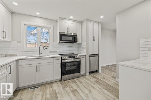 The property features a bright kitchen with white cabinetry, stainless steel appliances, and light-colored countertops - 12C Castle Terrace, Edmonton, AB - Indoor Photo Showing Kitchen With Upgraded Kitchen