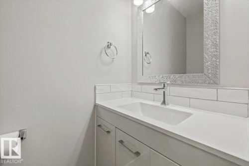 Bathroom vanity featuring a polished chrome faucet, a white countertop, and a decorative mirror with an ornate frame - 12C Castle Terrace, Edmonton, AB - Indoor Photo Showing Bathroom