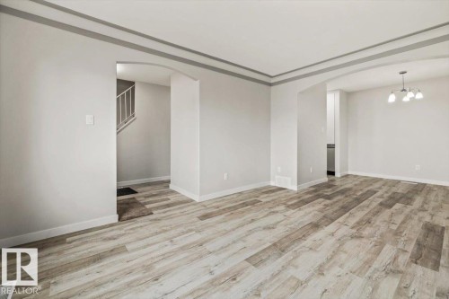 The property features light-colored plank flooring, neutral wall paint, and arched doorways - 12C Castle Terrace, Edmonton, AB - Indoor Photo Showing Other Room