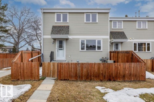 The property features a light-colored siding exterior, a front door with an awning, and a private fenced yard - 12C Castle Terrace, Edmonton, AB - Outdoor