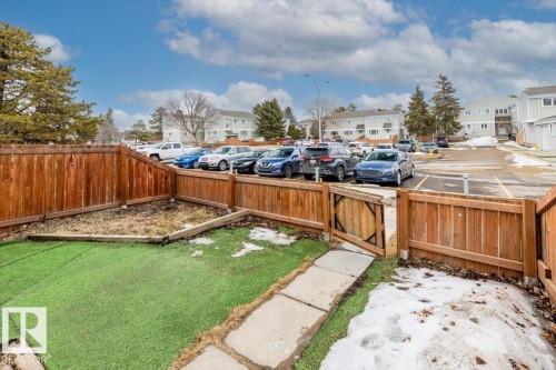 The property features a fenced yard with artificial turf and a paved walkway leading to a gate - 12C Castle Terrace, Edmonton, AB - Outdoor