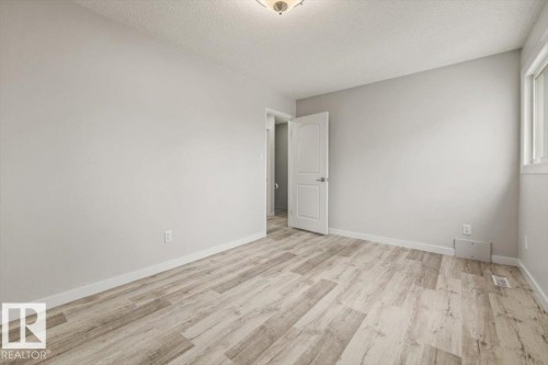 This room features light-toned wood-style flooring, a light-colored ceiling, and a window with white trim - 12C Castle Terrace, Edmonton, AB - Indoor Photo Showing Other Room
