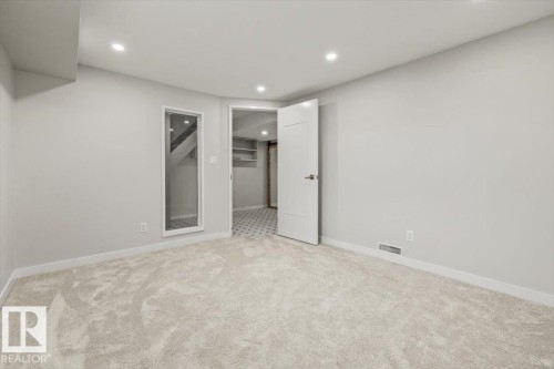 The property features a room with light grey walls and light colored carpeting, recessed lighting, and a white door with a modern handle - 12C Castle Terrace, Edmonton, AB - Indoor Photo Showing Other Room