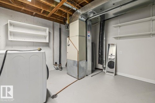 Utility area featuring a laundry appliance, built-in shelving, and exposed ceiling joists - 12C Castle Terrace, Edmonton, AB - Indoor Photo Showing Laundry Room