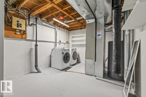 Dedicated laundry area featuring a washer and dryer, exposed ceiling joists, and utility shelving - 12C Castle Terrace, Edmonton, AB - Indoor Photo Showing Laundry Room